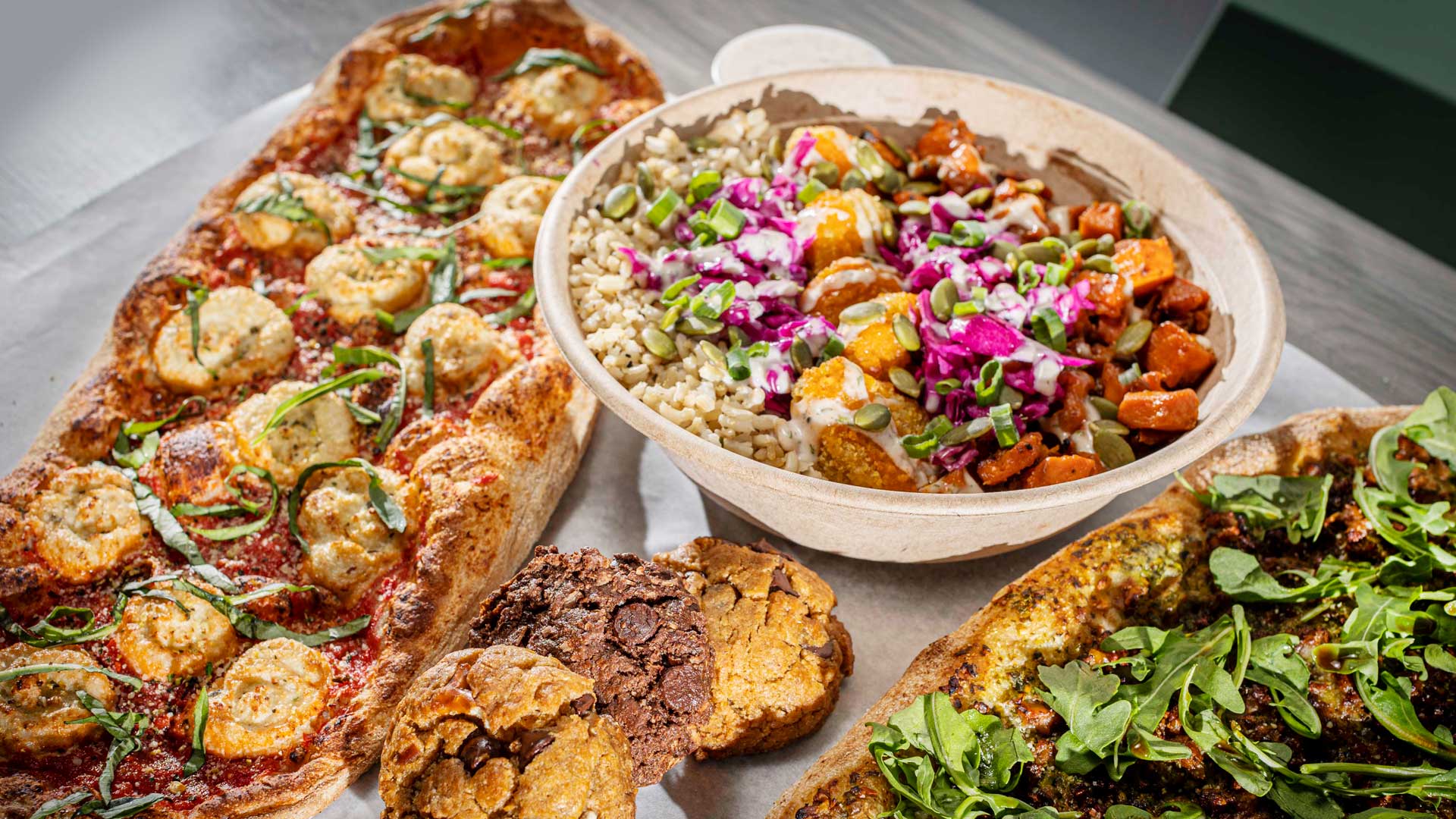 Menu offerings at Florish Plant-Based Pizza &amp; Bowls include, from left, the Margherita Pizza, Buffalo Soul Bowl, Sausage Pesto Pizza and homemade cookies. (Photography by Gabriel Burgos)