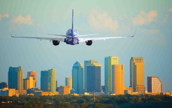 Passenger jet airliner plane arriving or departing Tampa Interna Tampa, Florida, skyline with warm sunset light with a commercial passenger jet airliner plane arriving or departing the International Airport.